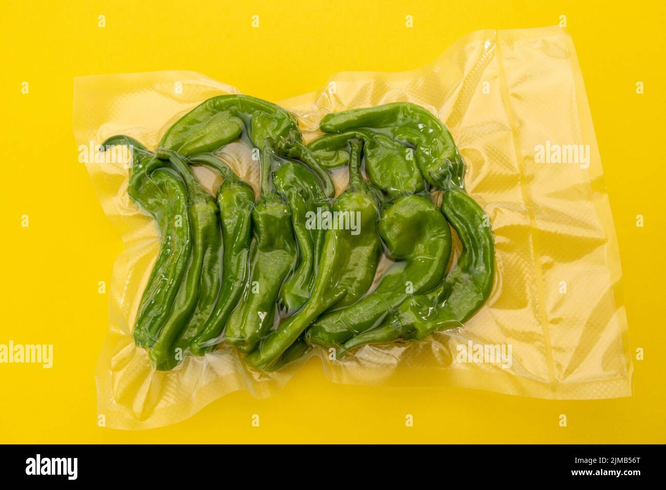 Friggitelli, toskanische oder griechische milde Paprika, auch Pepperoncini genannt, im Vakuum verpackt, versiegelt für Sous-Vide-Kochen isoliert auf gelbem Hintergrund oben Stockfoto