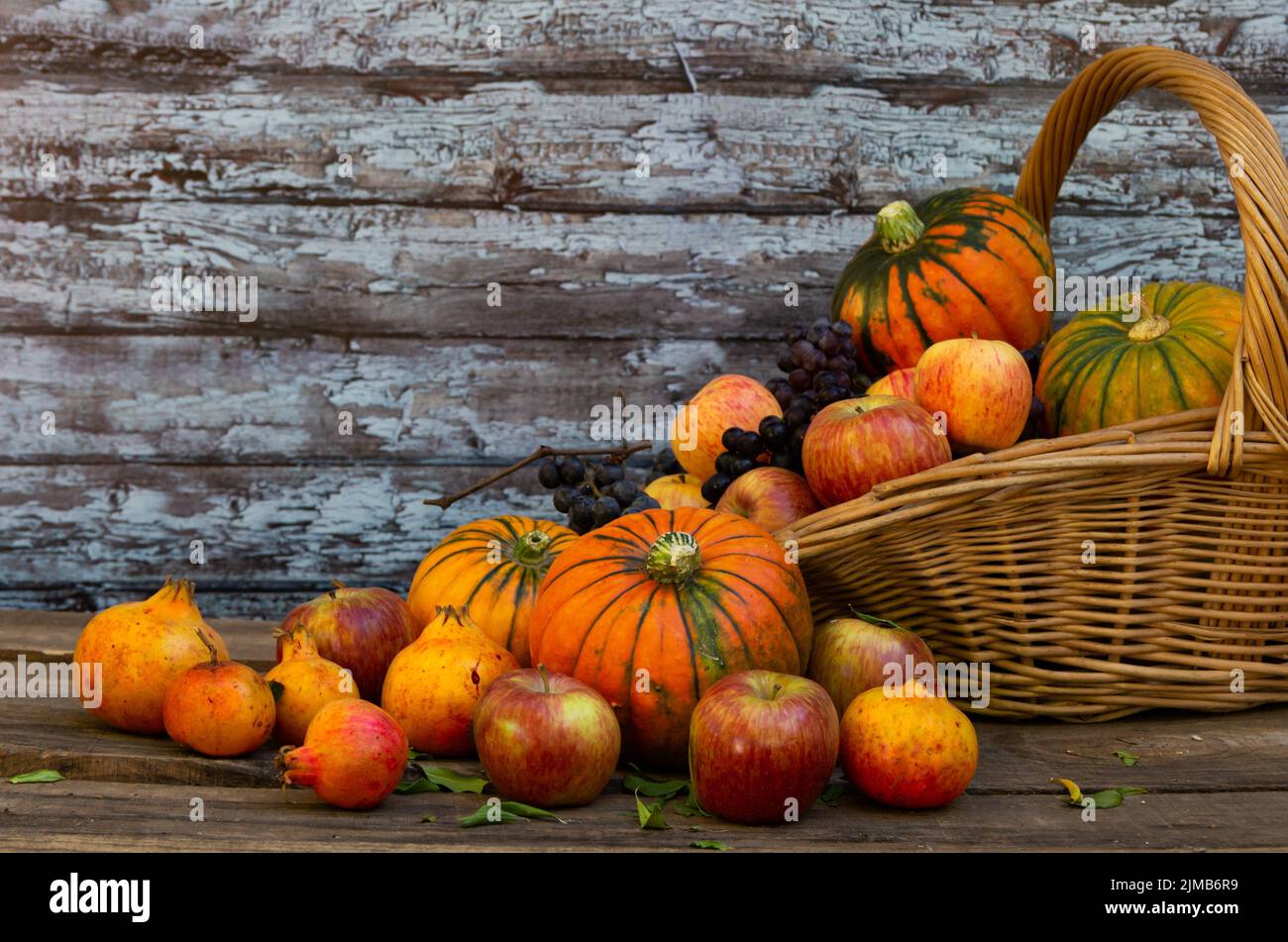 Korb voll von Kürbissen, Äpfeln und verschiedenen Herbstfrüchten und Blumen Stockfoto