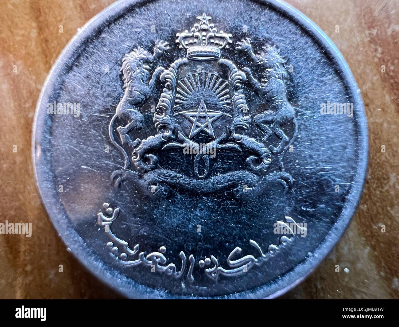 Nahaufnahme einer marokkanischen Dirham-Münze auf einem braunen Tisch Stockfoto