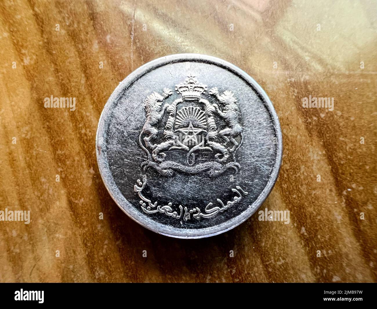 Eine Nahaufnahme einer halben marokkanischen Dirham-Münze auf einem braunen Tisch Stockfoto