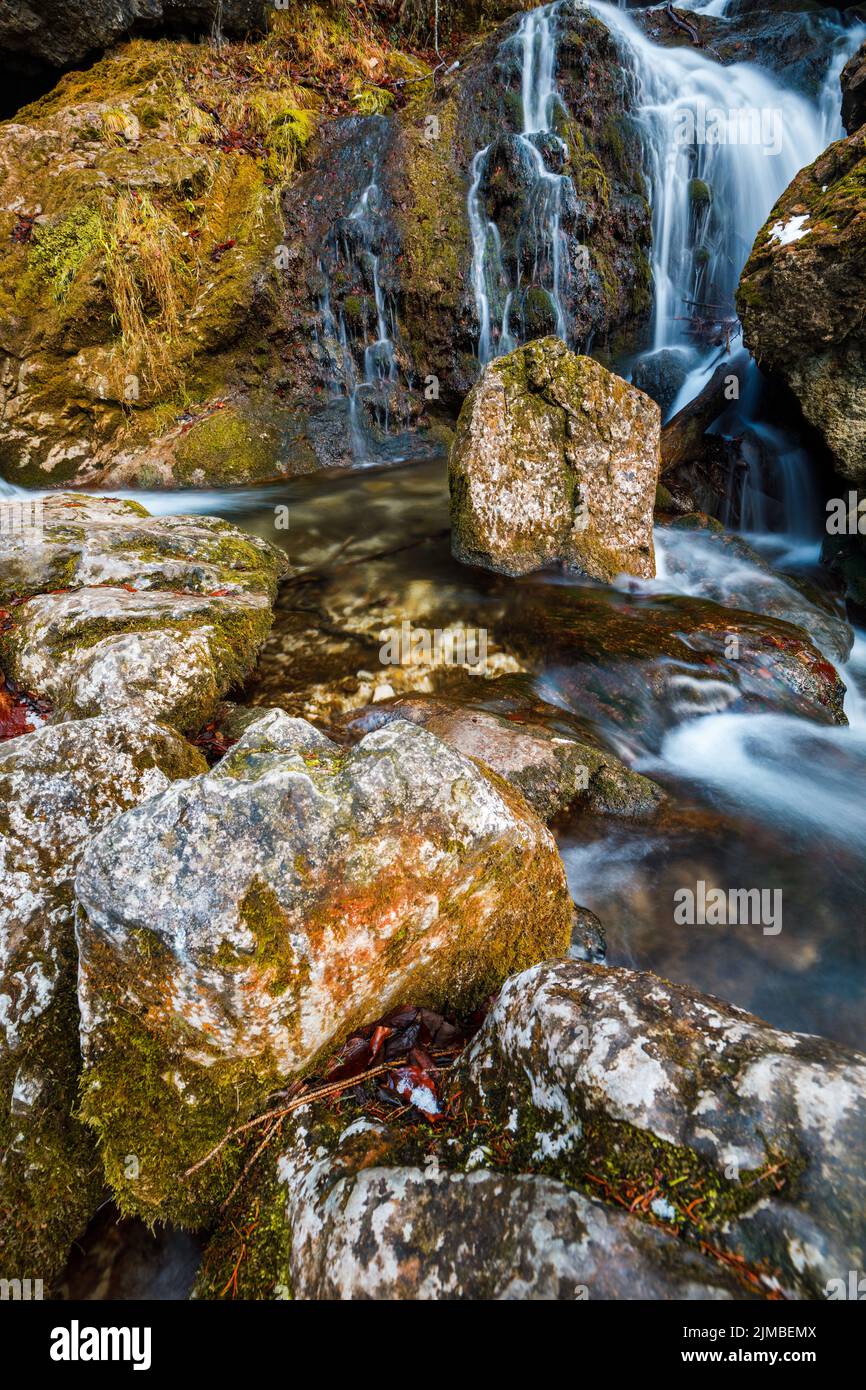 Schöner Wasserfall in Niederösterreich schoss an einem kalten Winternachmittag mit etwas Eis an den Seiten und grünem Moos, das auf Lo wächst Stockfoto