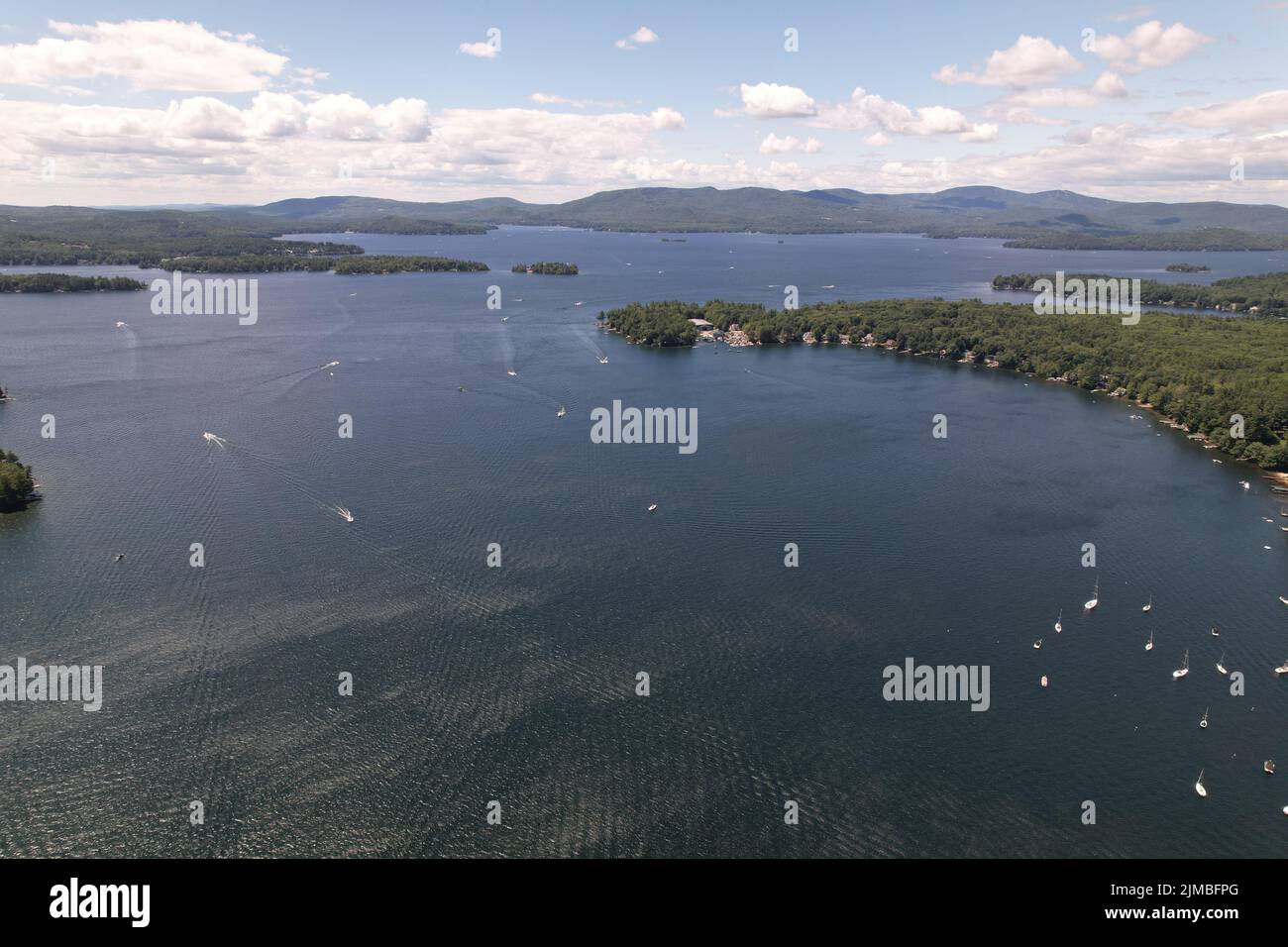 Eine Luftaufnahme des neu entdeckten Lake, NH mit Booten auf dem Wasser, Bäumen und Wolken im Hintergrund Stockfoto