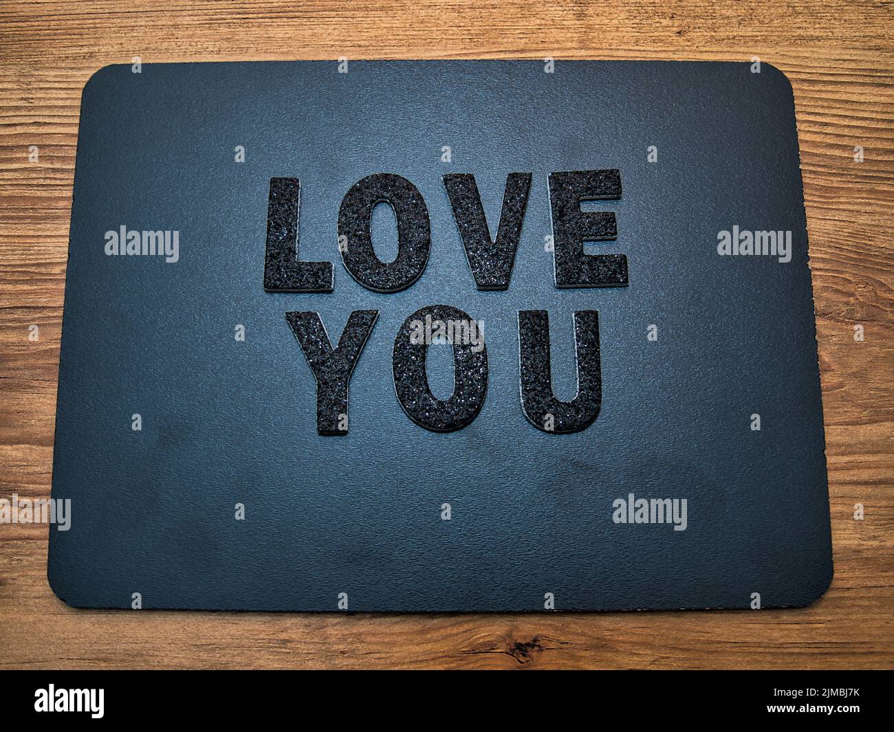 Die Worte Love You in schwarzen Buchstaben auf schwarzem Hintergrund. Perfekt für Happy Valentine's Day Social Media Beiträge. Stockfoto