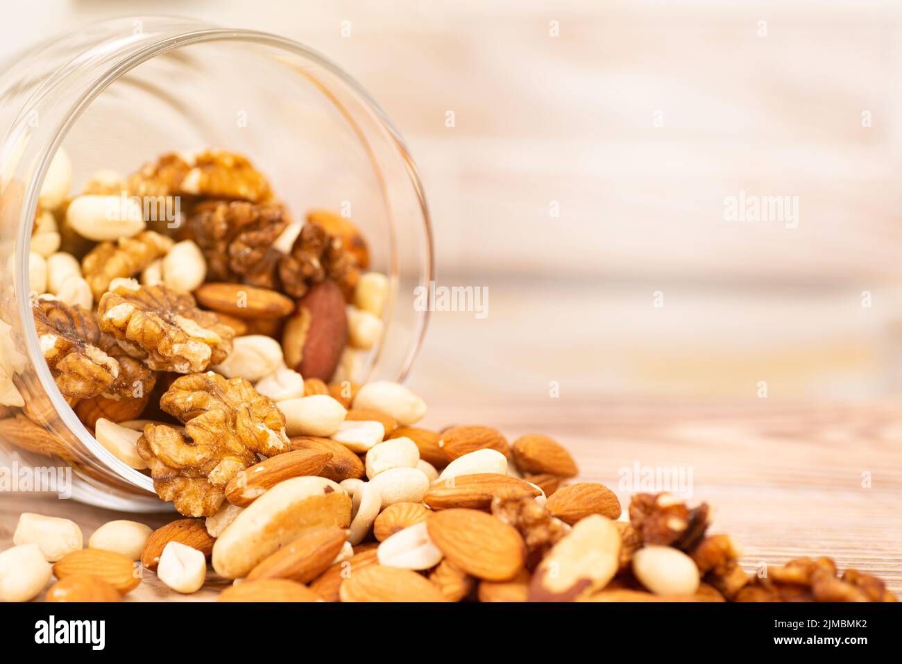 Aus einem Glas wird eine Mischung verschiedener Nüsse auf den Tisch gegossen Stockfoto