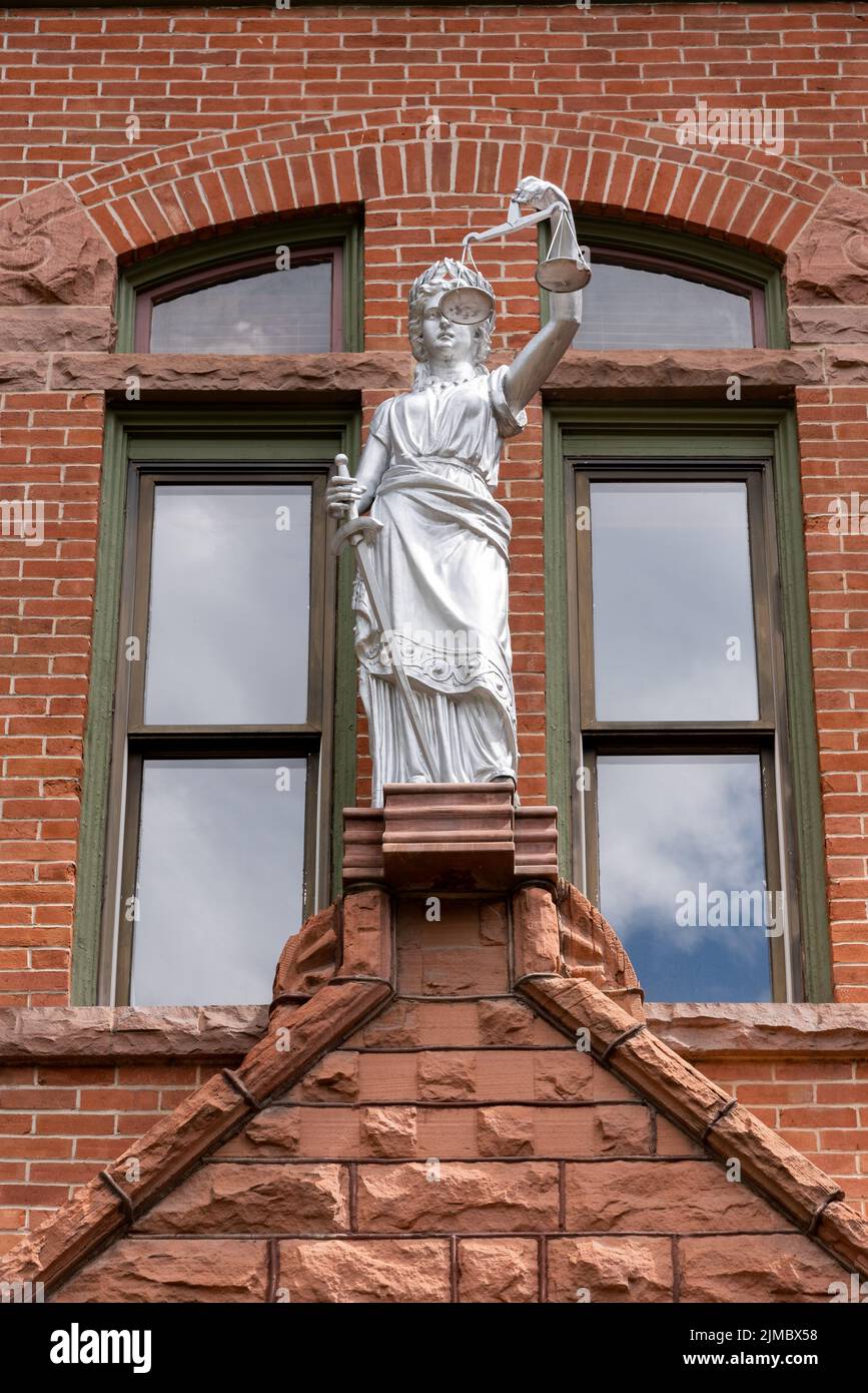 Statue von Lady Justice, ohne Augenbinde, silber bemalt, auf der Ziegelfassade des Pitkin County Courthouse, Aspen, Colorado. Stockfoto