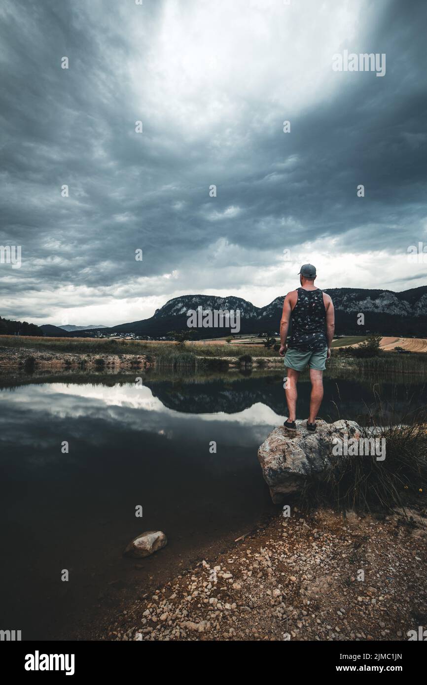 Junger Mann genießen den Blick auf einen Bergsee im Sommer. Berg in Wasser auf Hintergrund reflektieren. Stockfoto