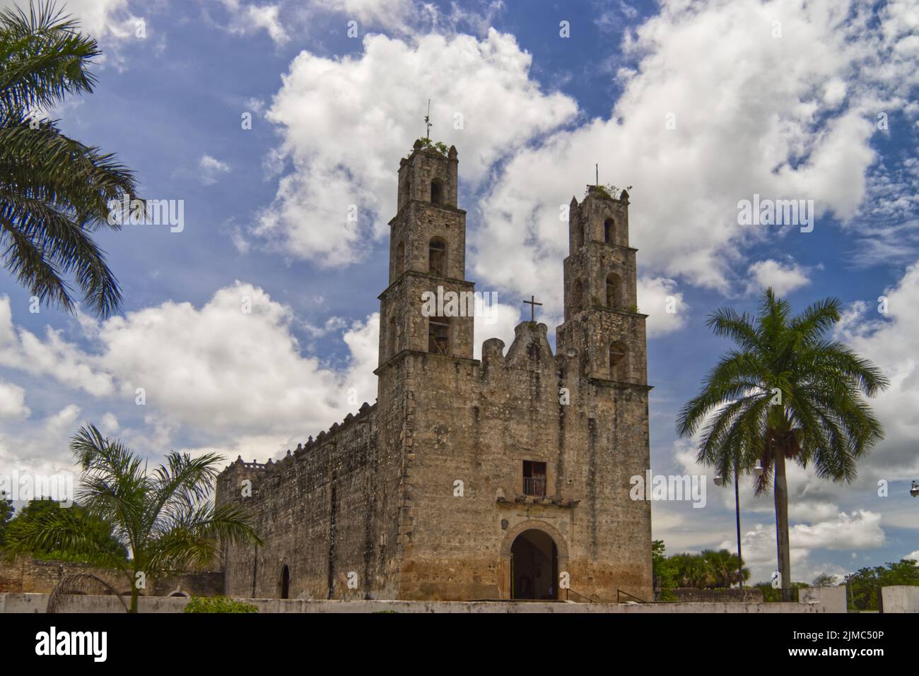 Typische Kirche von Mexiko Yucatan, blauer wolkig Himmel und Palmen Stockfoto