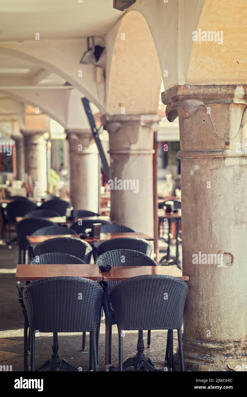 Leere Tische und Stühle von Coffee Bar im Freien Porticoed. Stockfoto