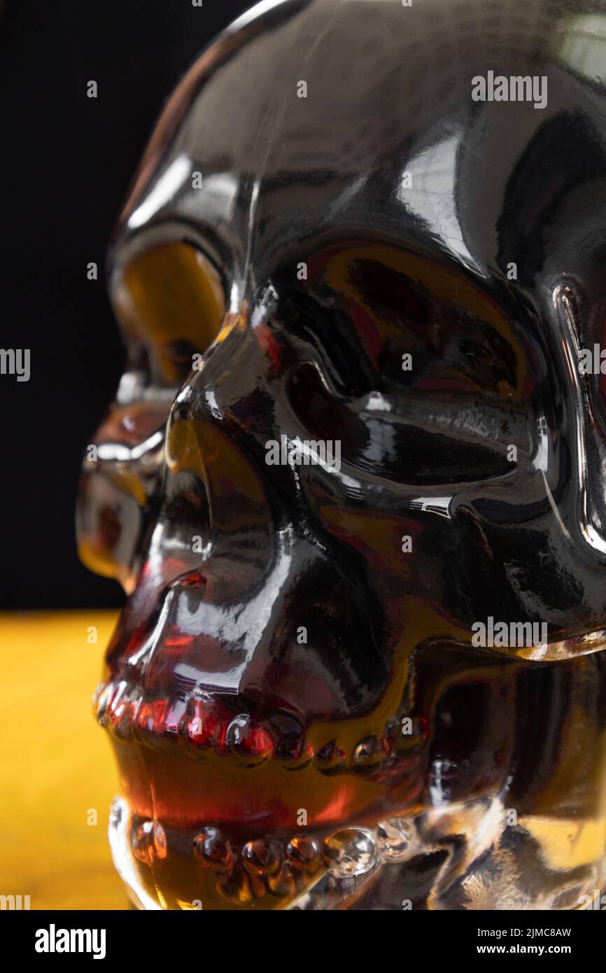 Details einer Glasflasche in Form eines Totenschädels mit einem Getränk im Atelier, Dekanter, dekorative Objekte Stockfoto