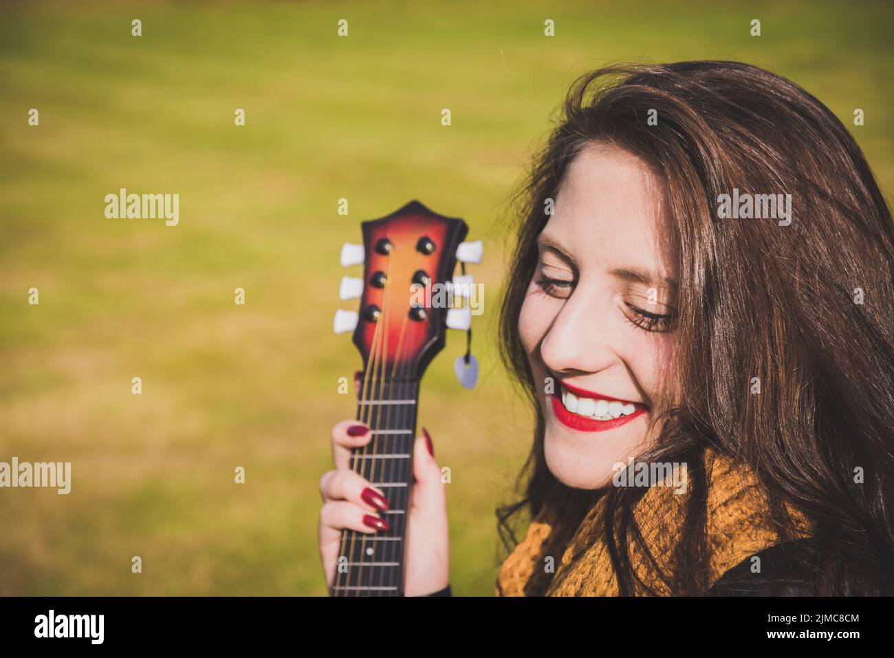 Lebhaft glückliche junge Frau mit einer Gitarre Stockfoto