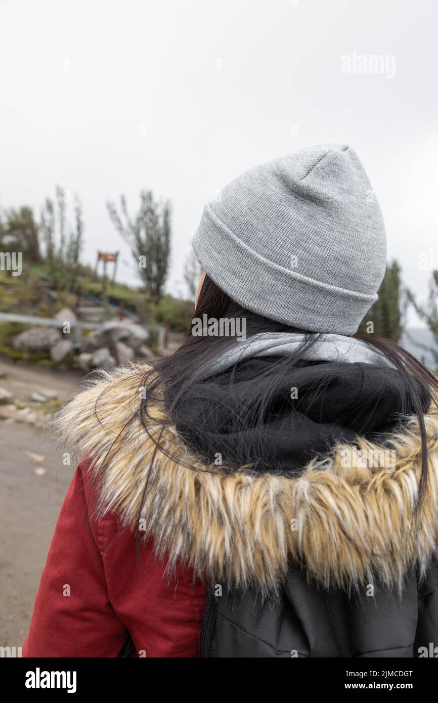 Zurückstehend eine Person, die eine Wollmütze und eine Jacke trägt, touristischer Lebensstil auf dem Land, ländliche Landschaft am Tag, Natur Stockfoto