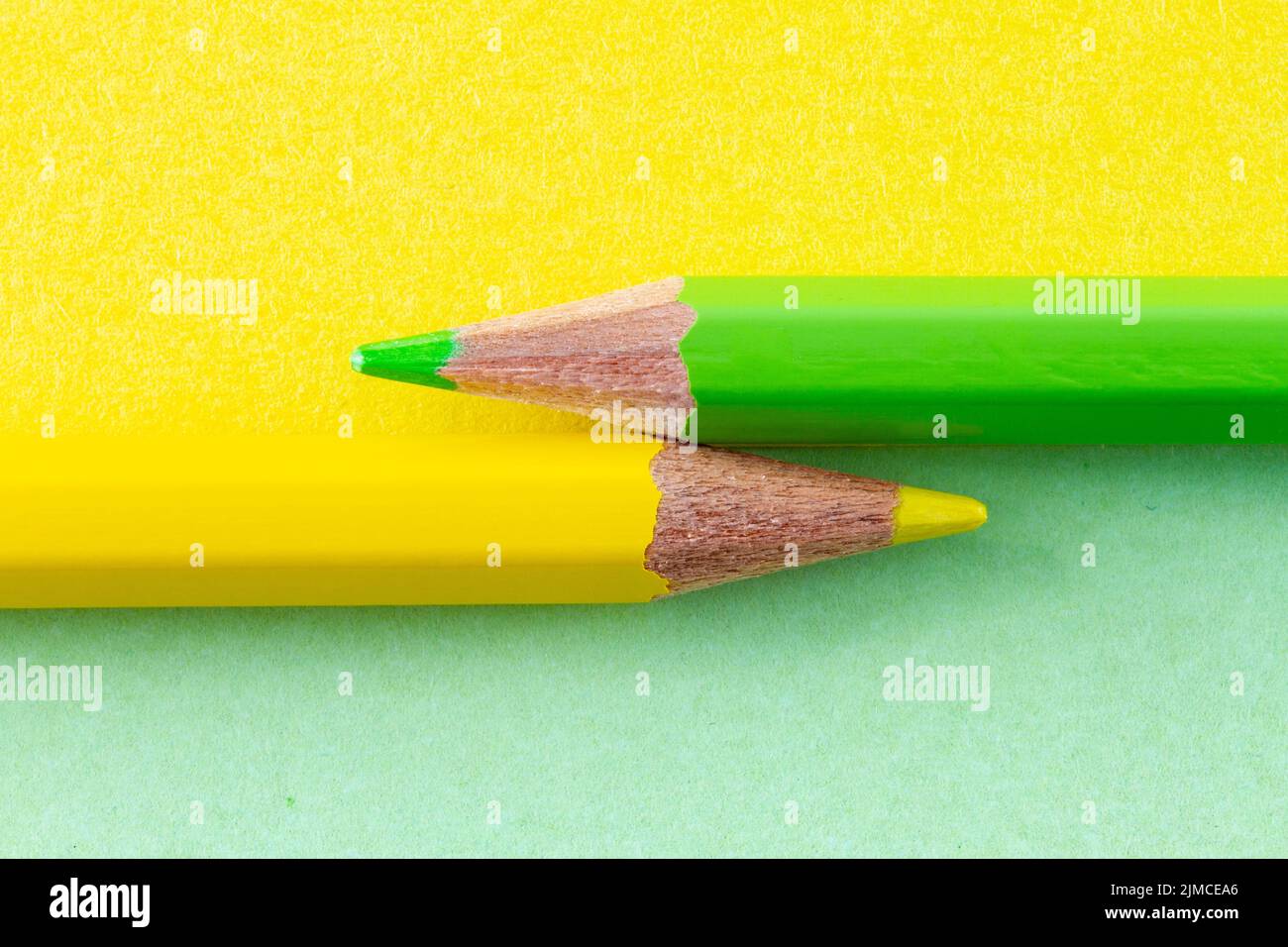 Farbstifte auf gelbem und grünem Papier, horizontal angeordnet. Stockfoto