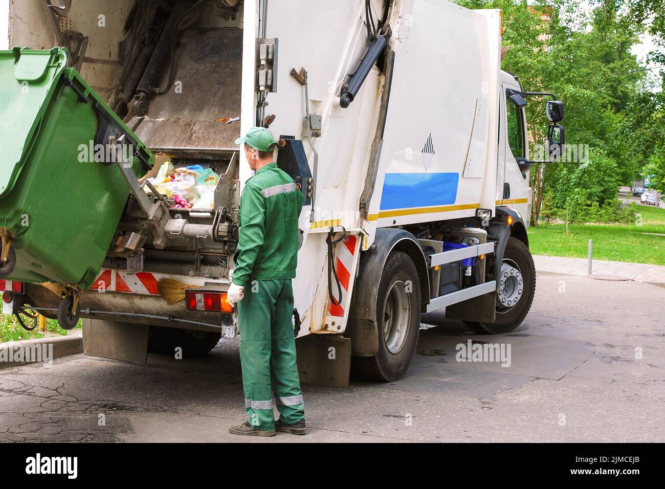 Müllsammler, der die Müllkompressorstrecke in einem Wohngebiet betreibt Stockfoto