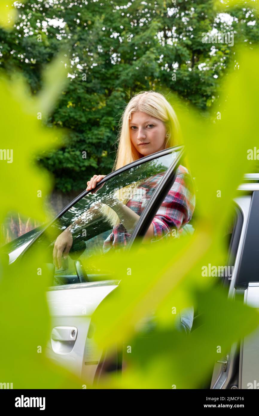 Eine blonde Frau zwischen einer offenen Autotür Stockfoto