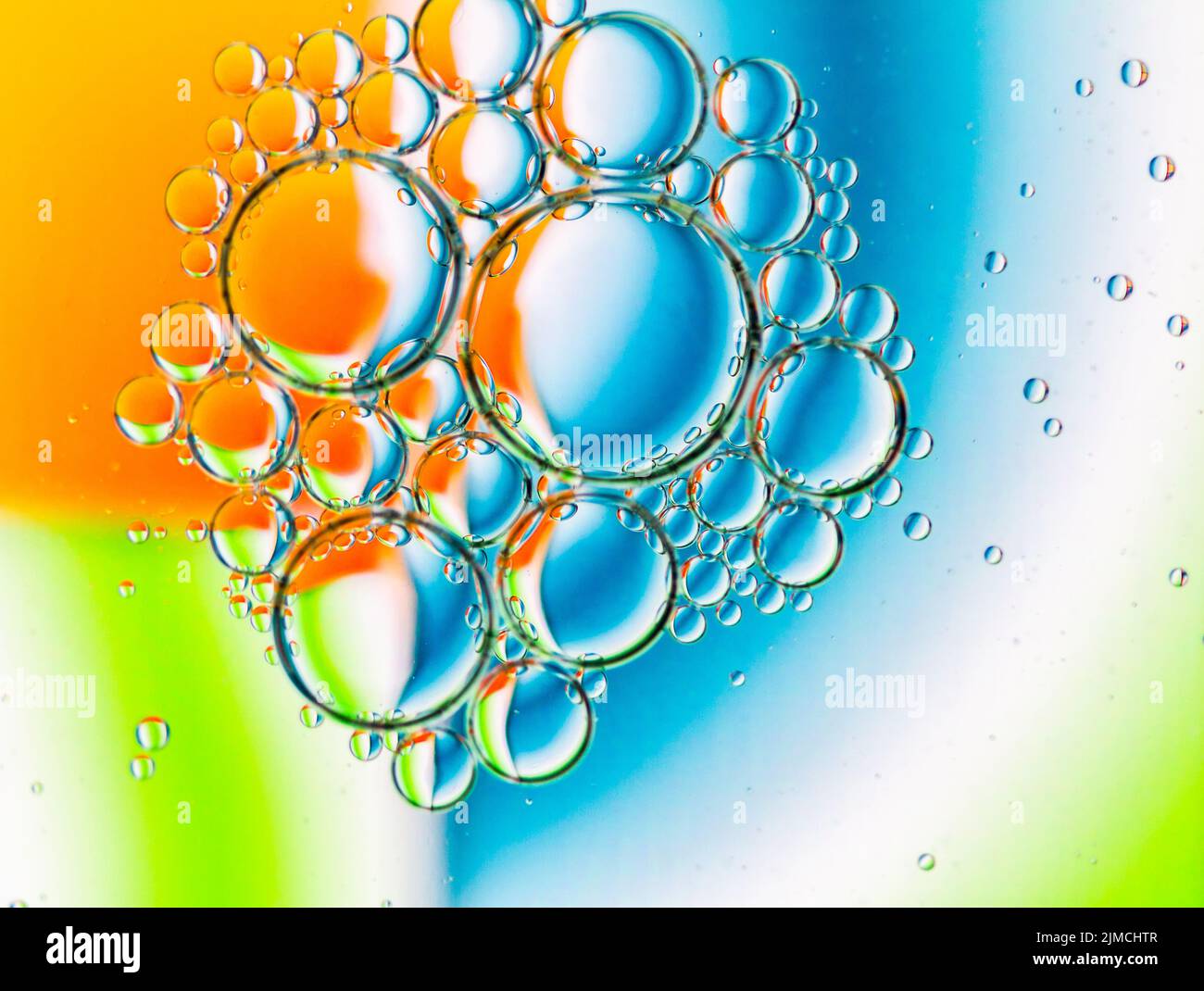 Abstrakter Hintergrund von Ölblasen auf Wasseroberfläche cyan orange grün bunte Palette. Stockfoto