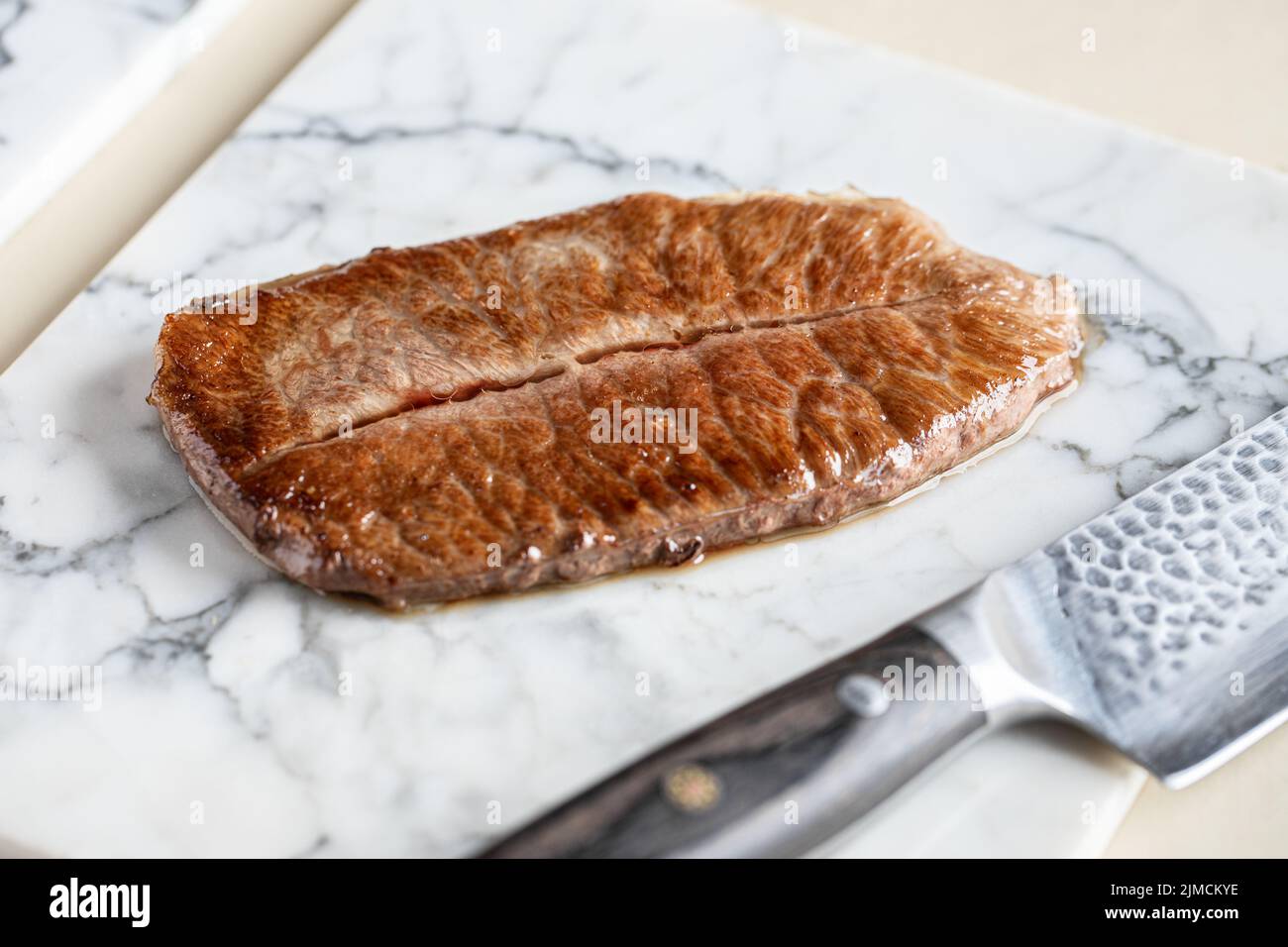 Von oben von leckeren kobe Präfektur Wagyu Rindfleisch serviert auf Marmor Schneidebrett in der Nähe von scharfen Messer in der hellen Küche während des Kochvorgangs Stockfoto