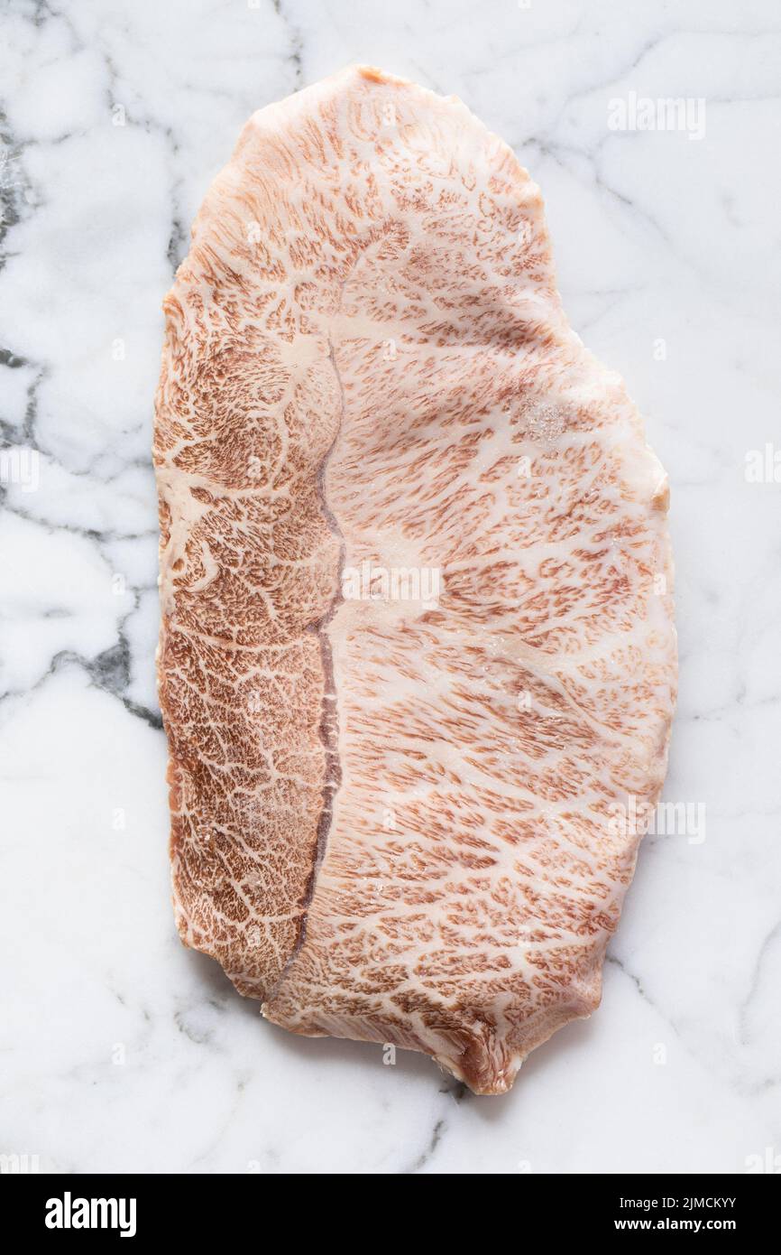 Blick von oben auf das traditionelle japanische, ungekochte wagyu-Rindfleisch der Präfektur kobe, das während der Zubereitung auf einem Marmortisch im hellen Raum aufgestellt wurde Stockfoto