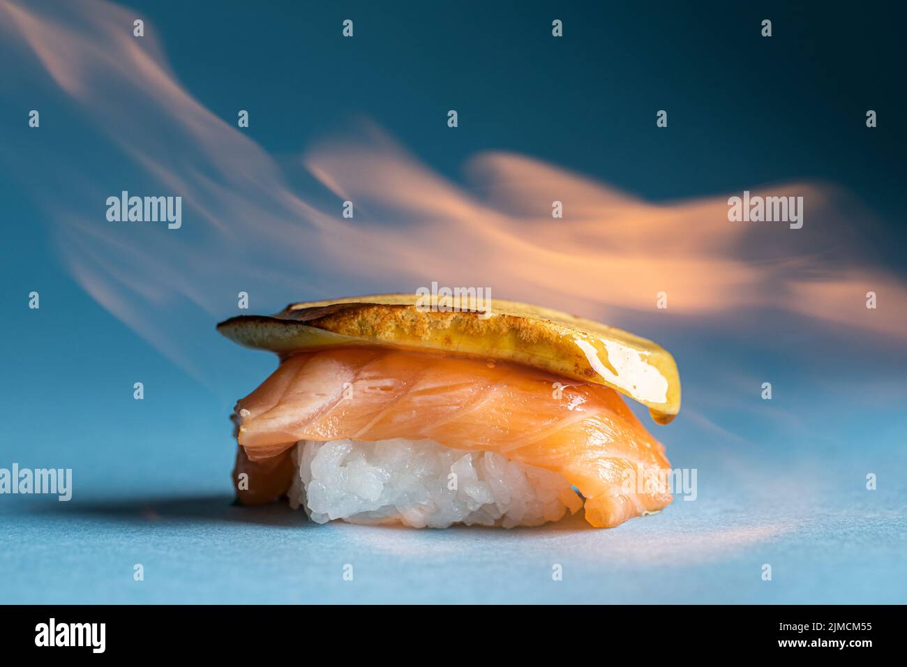 Leckere traditionelle japanische norwegische Nigiri mit frischem Lachs und köstlichen flambeed Foie Gras vor blauem Hintergrund im hellen Studio platziert Stockfoto