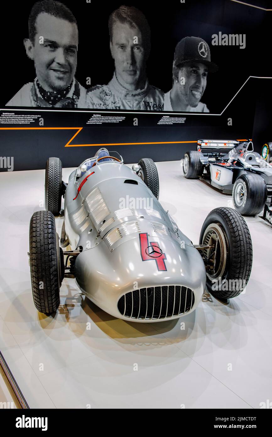 Historischer Mercedes Silver Arrow Rennwagen von Rudolf Caracciola, im Hintergrund Foto von links Rudolf Caracciola, Mitte Mika Haekkinen, rechts Stockfoto