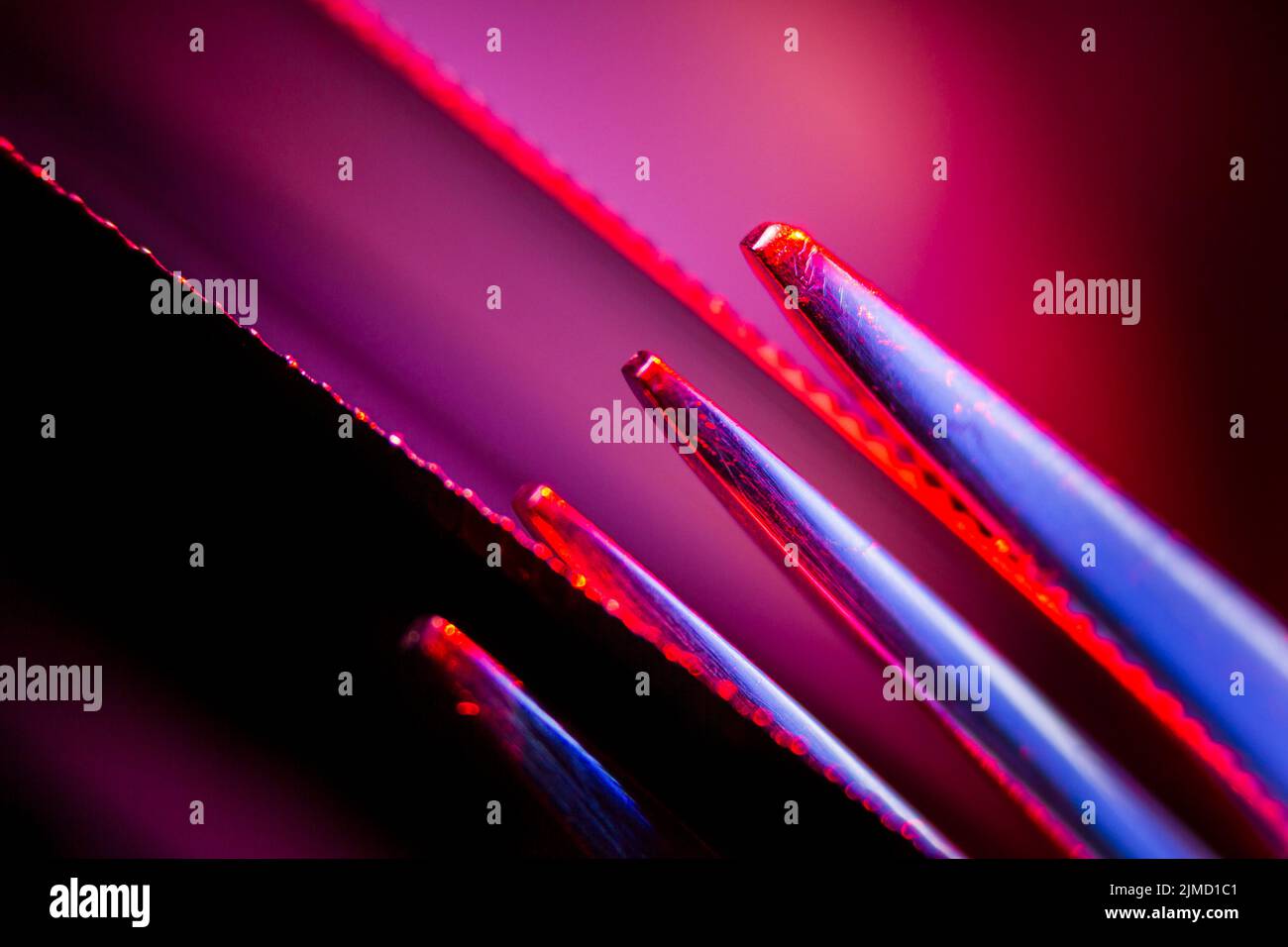 Kanten von zwei beleuchteten gezackten Messern und Zinken einer Gabel Makroaufnahme als Hintergrund geeignet. Stockfoto