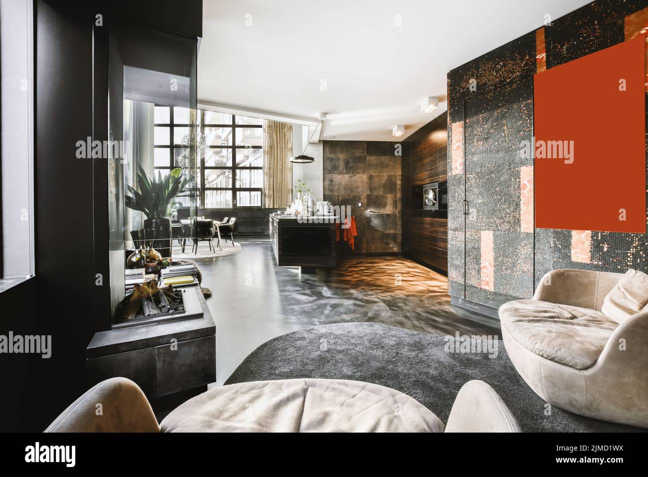 Interieur des modernen Wohnzimmers mit komfortablen Sesseln auf Teppich gegenüber Kamin und im Hintergrund Luxus-Küche eingerichtet Stockfoto