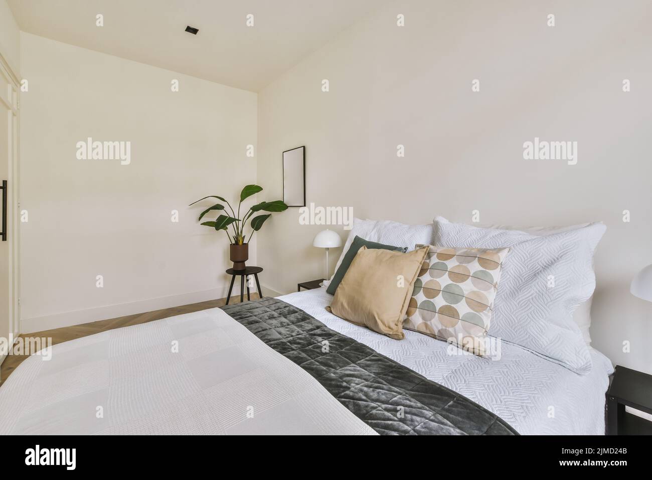 Modernes, weißes und beleuchtetes Schlafzimmer mit großem Bett und minimaler Dekoration und Möbeln Stockfoto