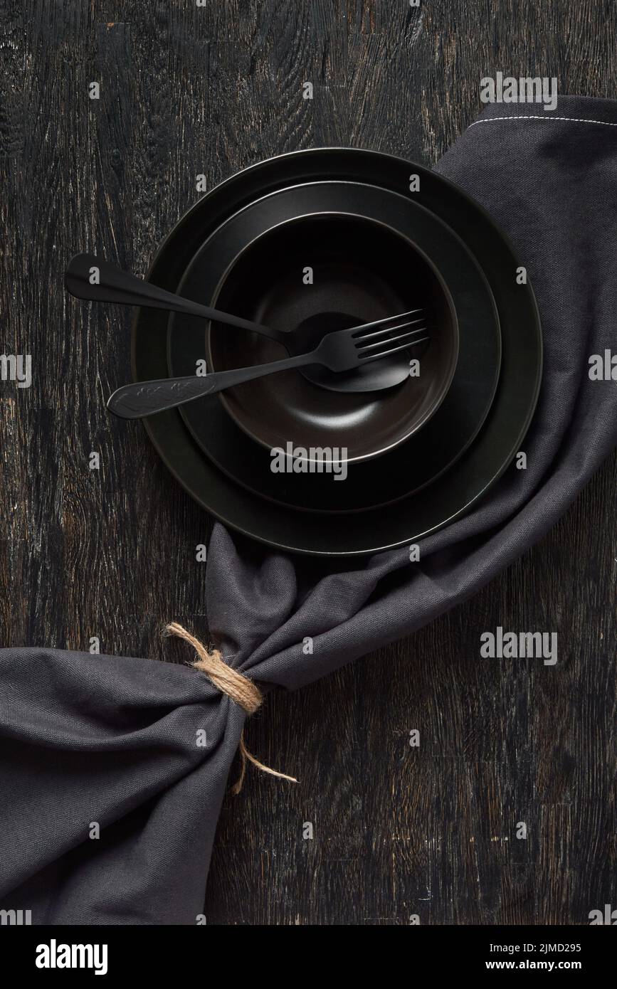 Serviert Küchentisch mit Kochgeschirr und Textilserviette in schwarzen Farben. Stockfoto