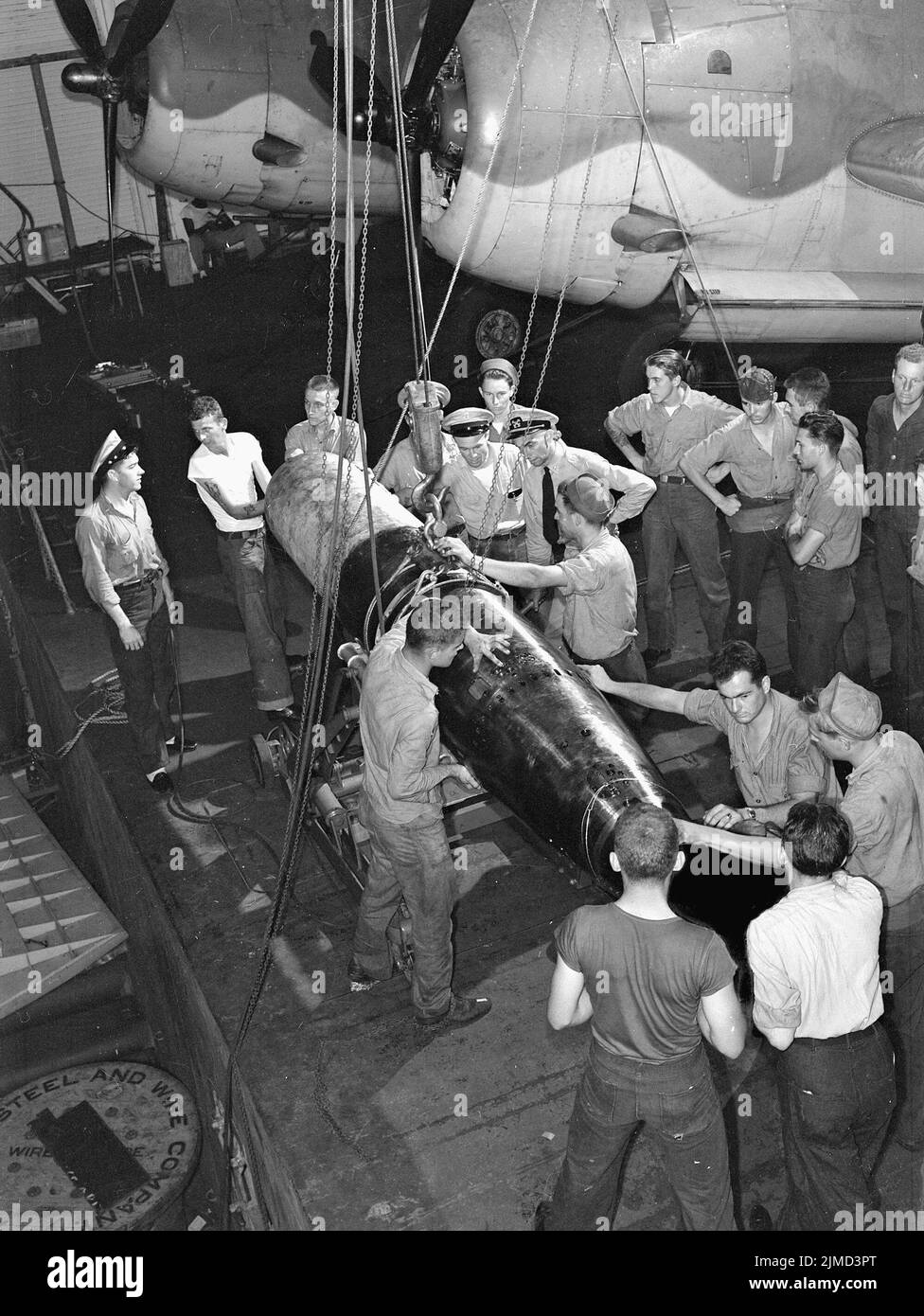 Die Flugbesatzung bereitet einen Torpedo an Bord einer US-amerikanischen Fluggesellschaft vor, wobei Grumman Avenger Torpedo-Bomber im Hintergrund sind. Stockfoto