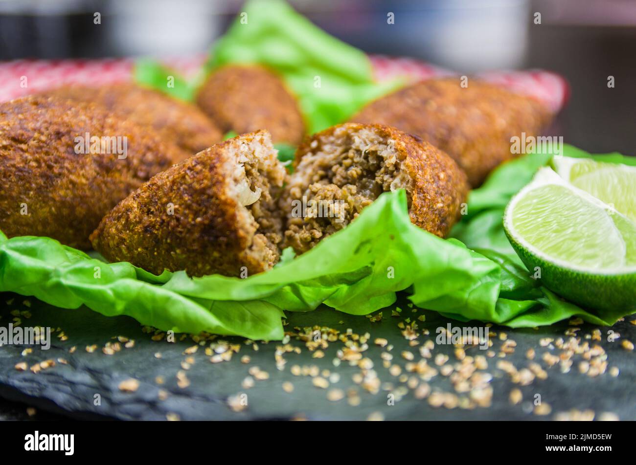 Köstliche libanesische Gerichte, Kibbeh (Kibe) mit Saucen und Zitrone auf schwarzem Schiefer und Granitrückstand Stockfoto