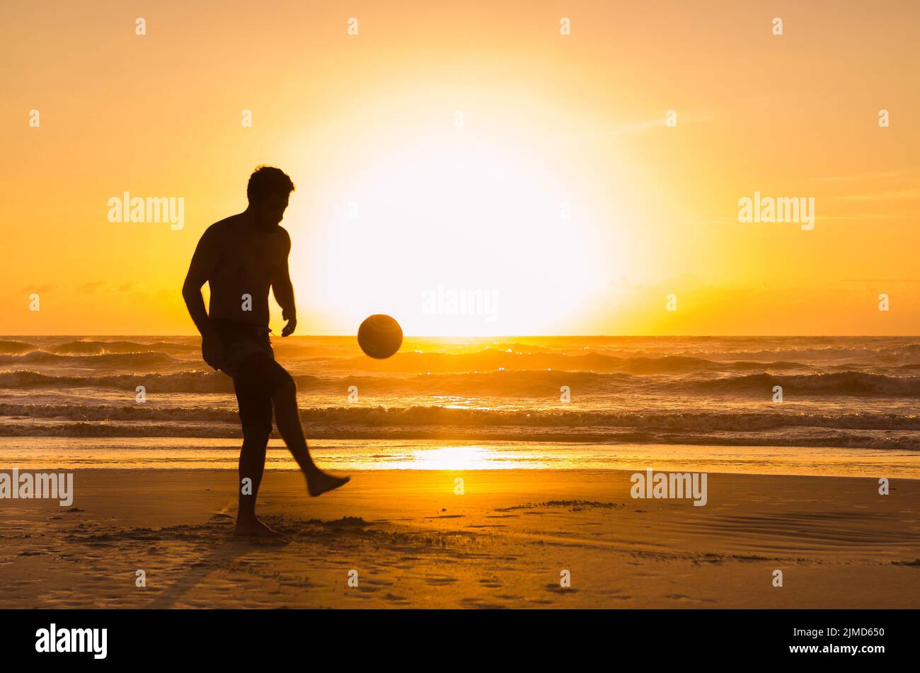 Tolles Konzept von Fußball, Mann spielt Fußball am Strand in der goldenen Stunde, Sonnenuntergang. Anmachen von Anhalten Stockfoto