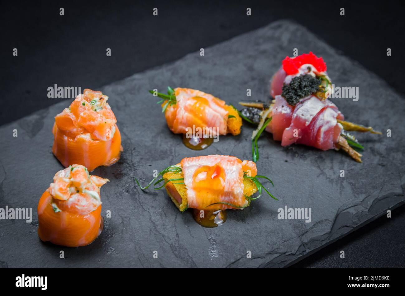 Sushi, traditionelle japanische Küche. Mehrere leckere Sushi auf dem dekorierten Teller, schwarzer Backgroun Stockfoto