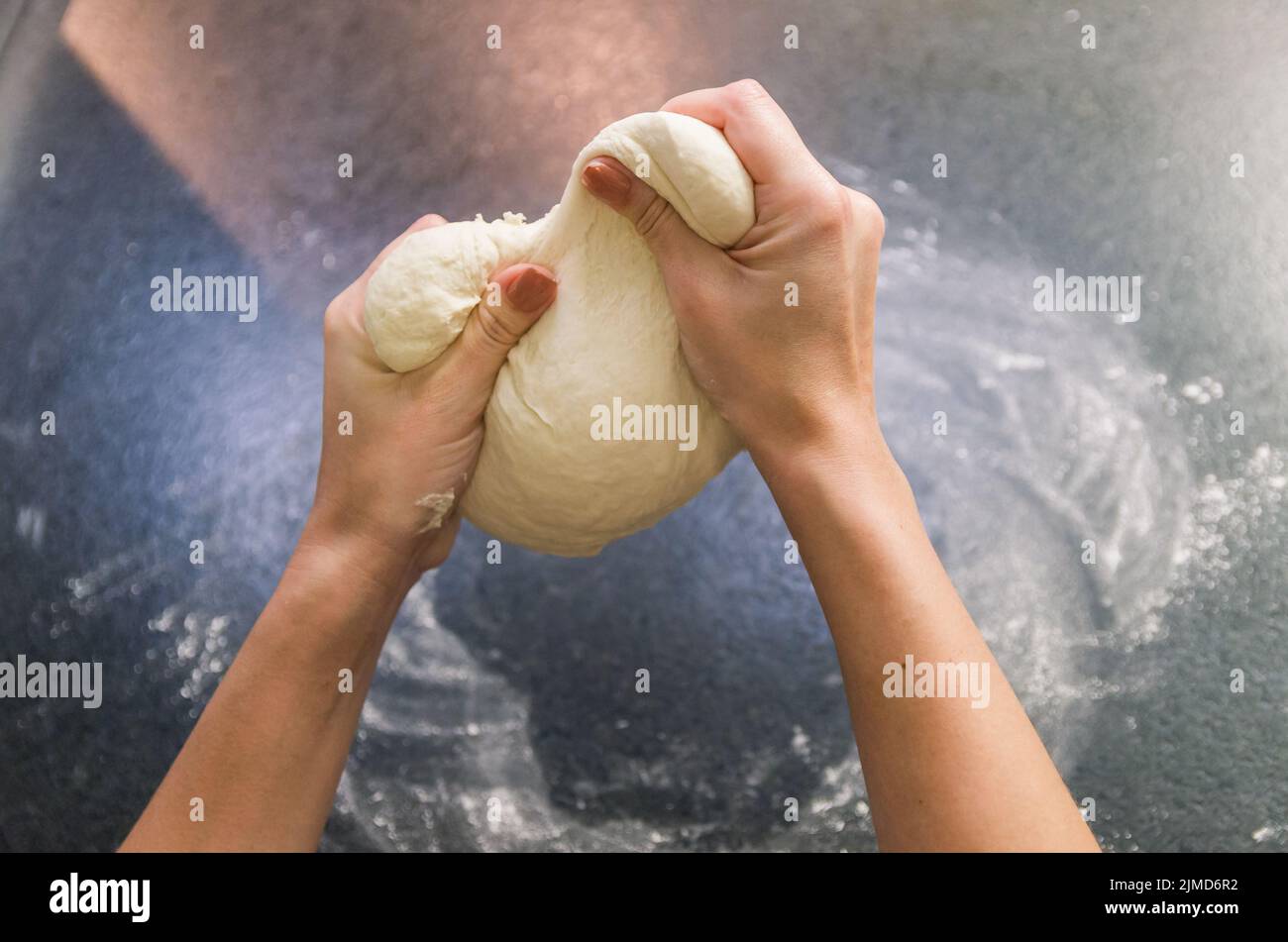 Frau Vorbereitung Pizza Teig auf schwarzem Granit Tisch Stockfoto