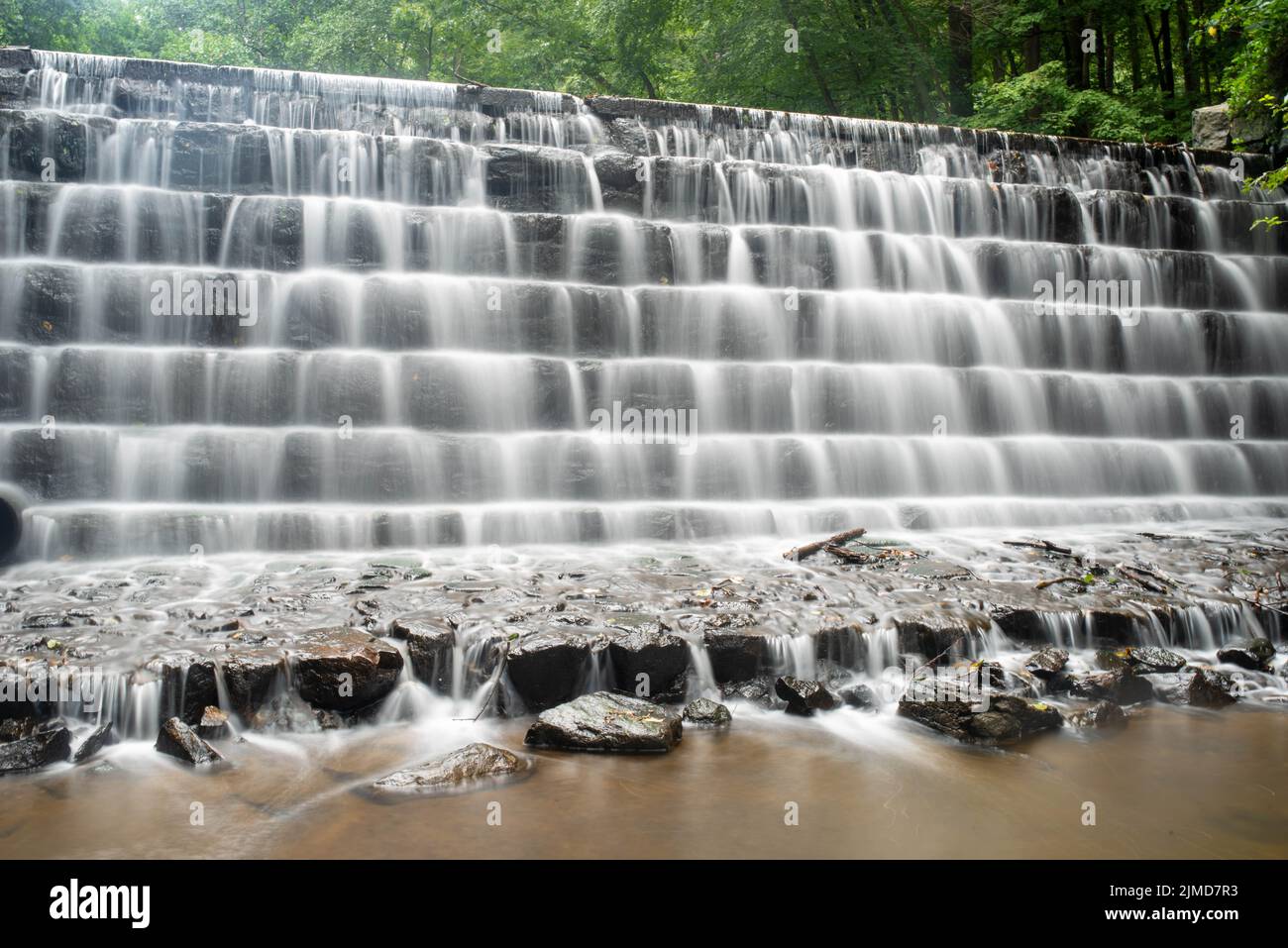 Langgestrecktes Wasser, das in einem Waldbach durch eine abgestufte Felswand stürzt Stockfoto