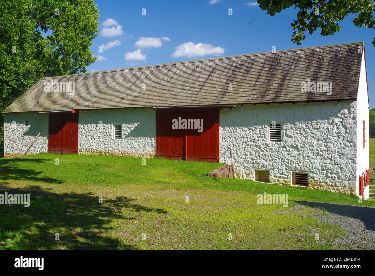 Historische koloniale amerikanische Steinscheune mit roten Türen Stockfoto