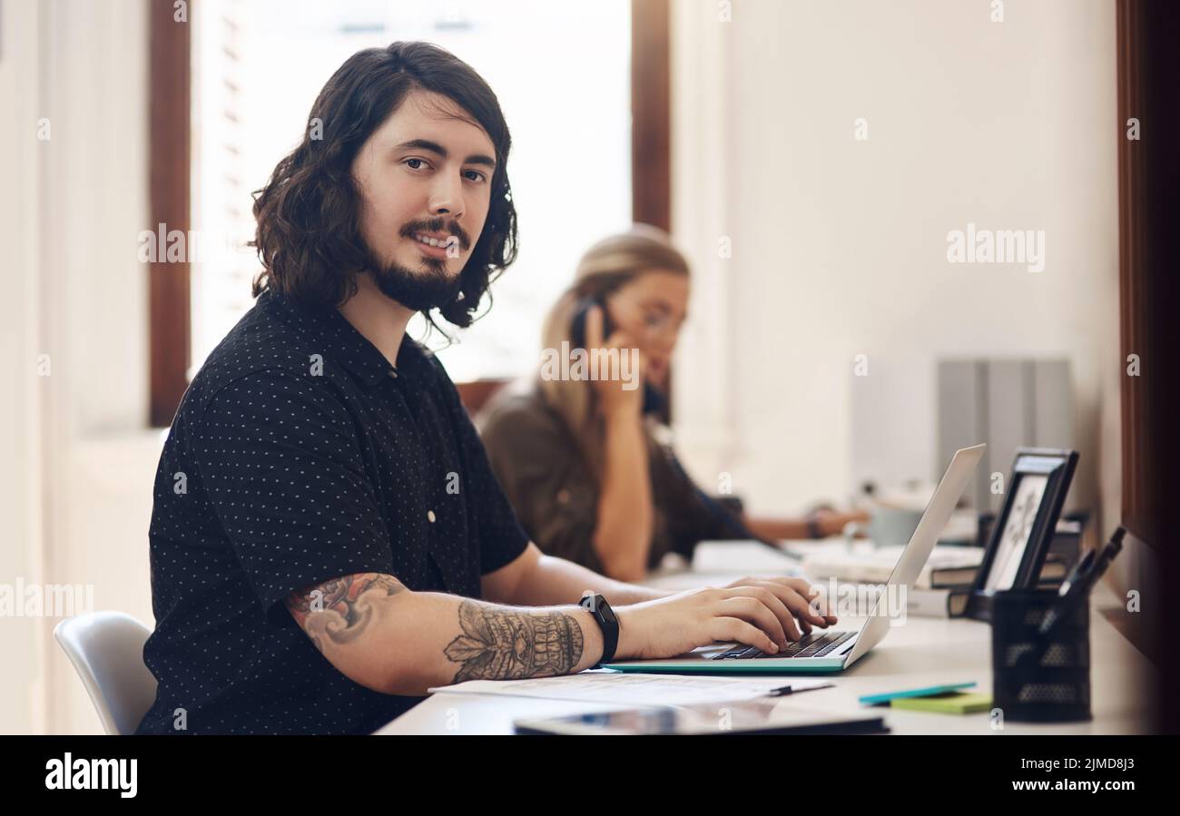 Wenn Sie Leidenschaft für Ihr Unternehmen haben, wird es gedeihen. Porträt eines jungen Geschäftsmannes, der in einem Büro mit seinem Kollegen im Hintergrund arbeitet. Stockfoto