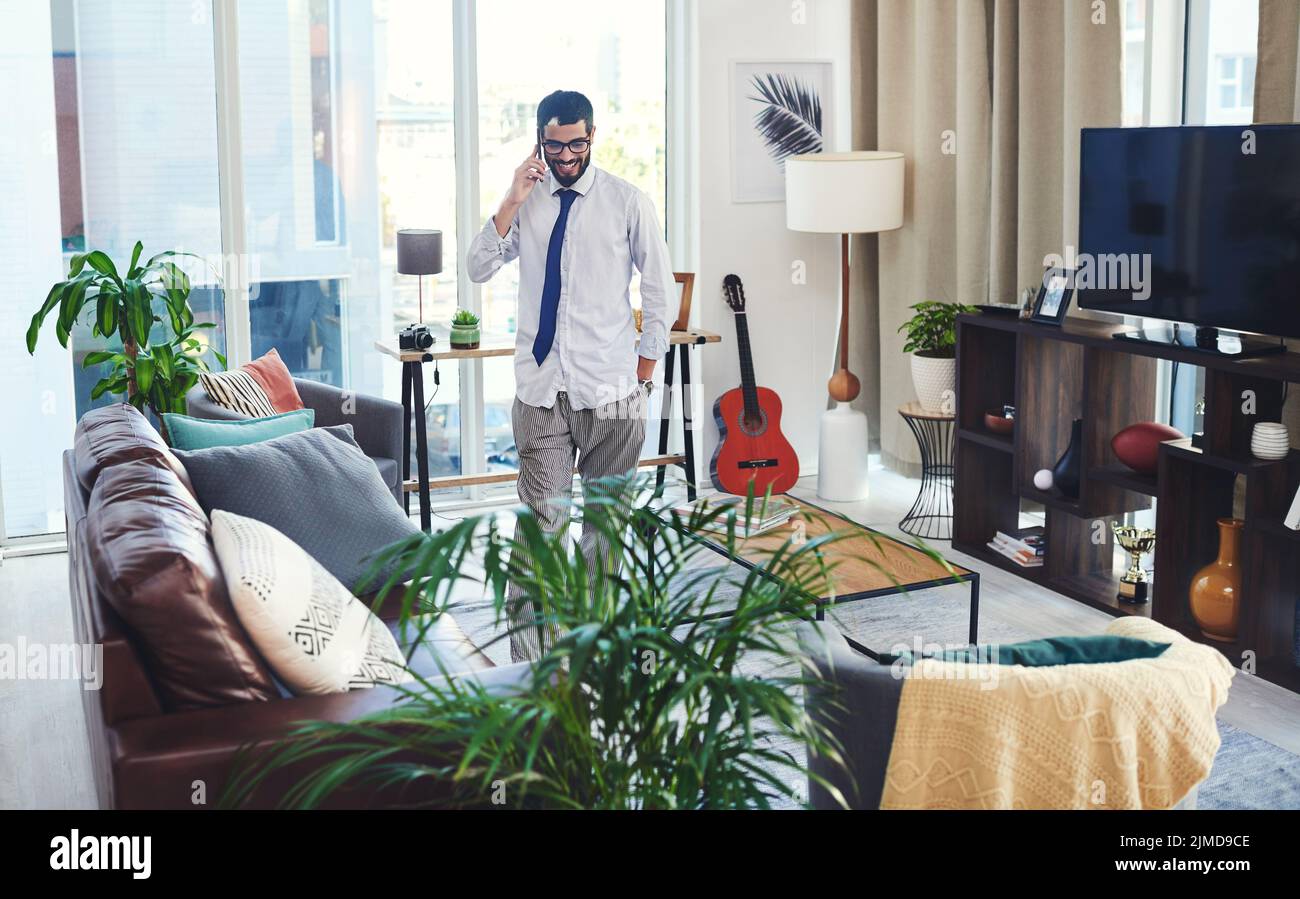 Ein Mann, der von zu Hause aus auf seinem Handy spricht, während er von zu Hause aus arbeitet, sieht ein wenig anders aus. Stockfoto