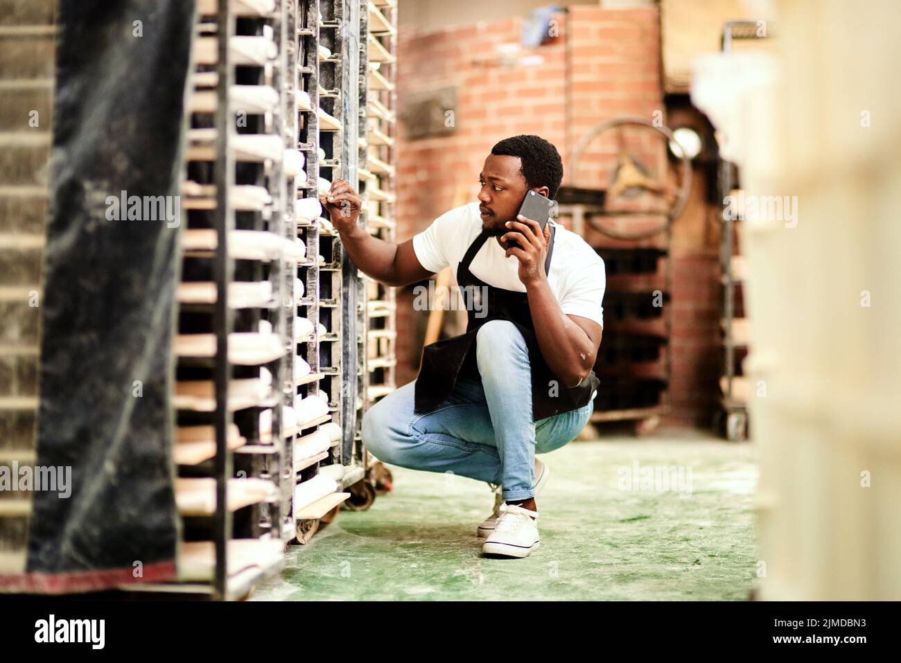 Ich habe eine massive Bestellung für heute, Ich brauche etwas Zutat so schnell. Ein männlicher Bäcker reden am Telefon, während mit der Überprüfung eines Backwagens beschäftigt. Stockfoto