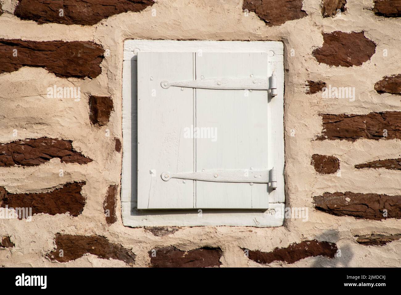 Kolonialer Fensterrahmen mit Fensterläden in Steinmauer Stockfoto
