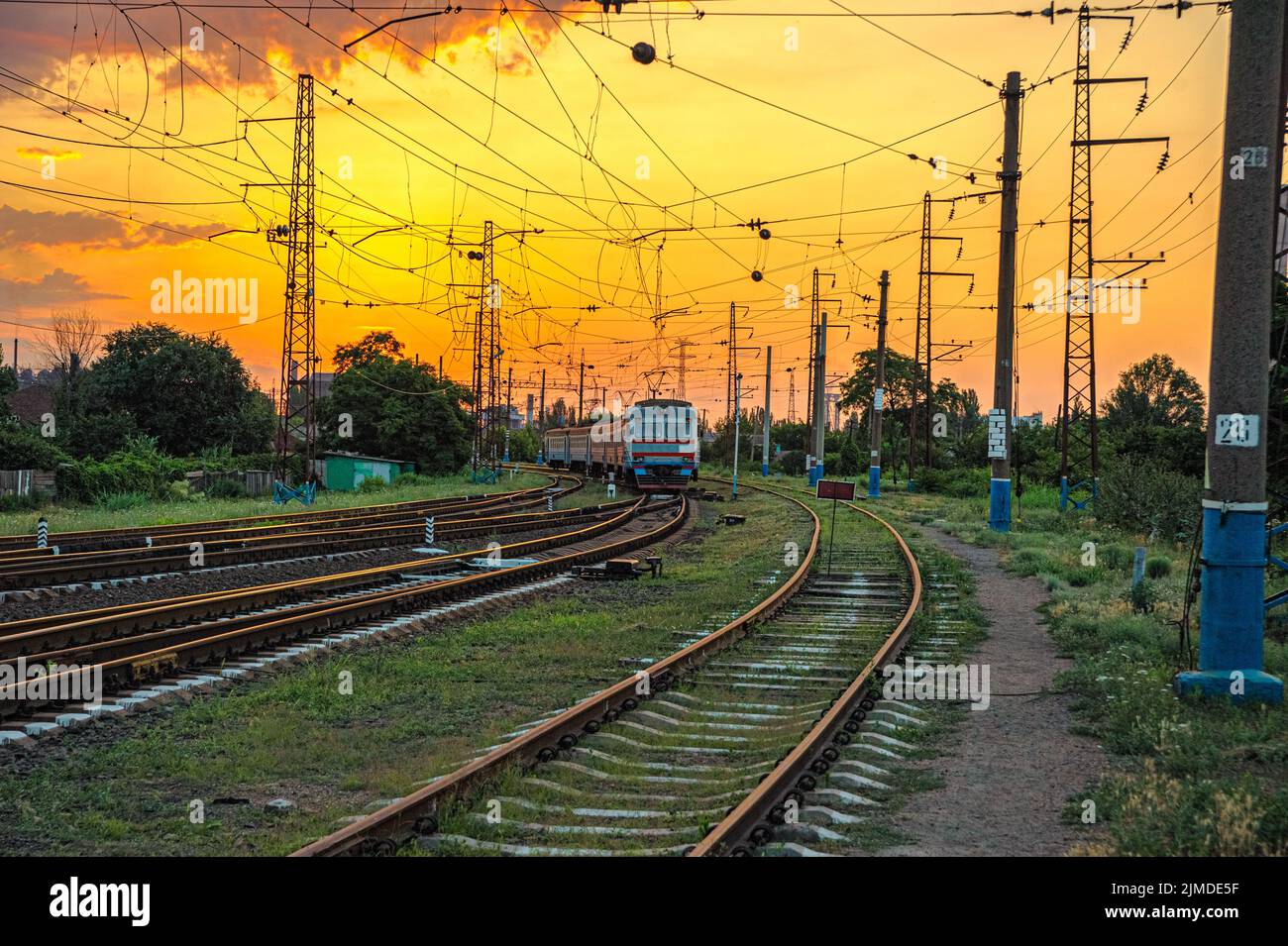 Alter Elektrozug auf Eisenbahnen am Eingang zum Bahnhof bei Sonnenaufgang in Mariupol, Ukraine Stockfoto