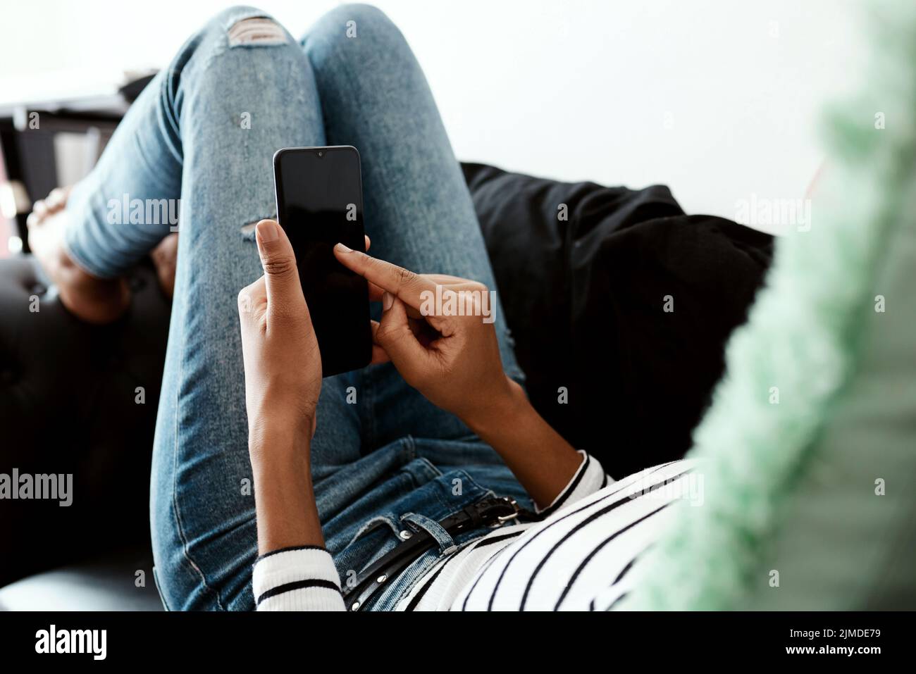 Und schicken Sie... eine Frau, die ein Smartphone auf dem Sofa zu Hause benutzt. Stockfoto