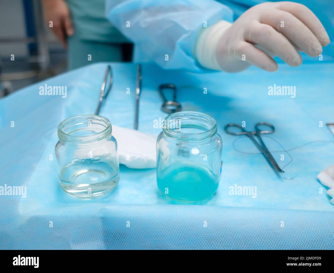 Sterile chirurgische Instrumente und Glasbehälter mit Lösungen auf dem Tisch während eines chirurgischen Eingriffs. Stockfoto
