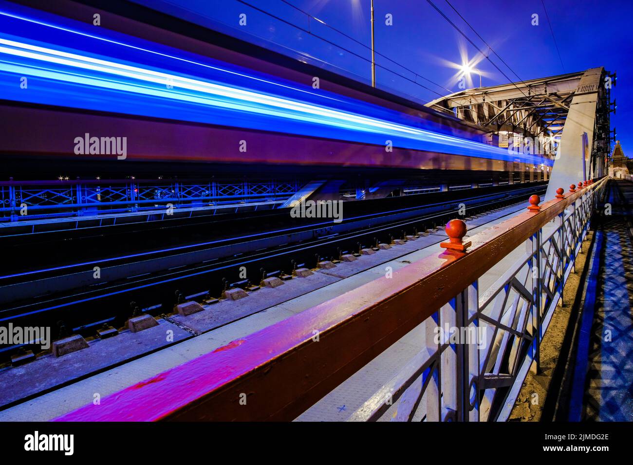 Verschwommene Lichtstreifen aus einem rasenden Zug. Der Zug fährt nachts durch die Bögen der Eisenbahnbrücke. Stockfoto
