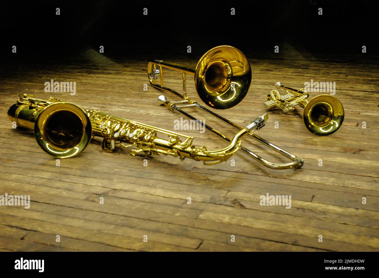 Gelbe Blas- und Blasinstrumente - Saxofon, Posaune, Trompete auf der Bühne mit Hintergrundbeleuchtung Stockfoto