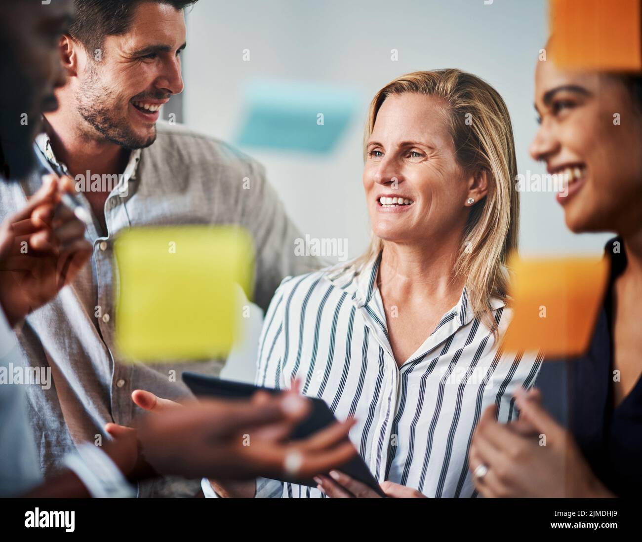 Sie planen gemeinsam. Gemeinsam gelingt es ihnen. Eine Gruppe von Geschäftskollegen, die in ihrem Büro auf einem Glaswischbrett Brainstorming durchführen. Stockfoto