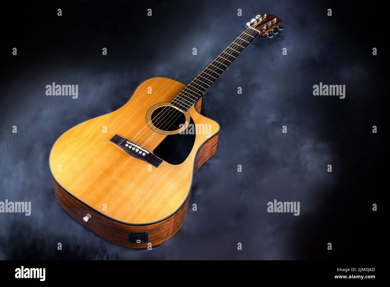 Akustische klassische gelbe 6-saitige Gitarre mit schwarzem Schlagbrett in Rauch auf schwarzem isolierten Hintergrund Stockfoto