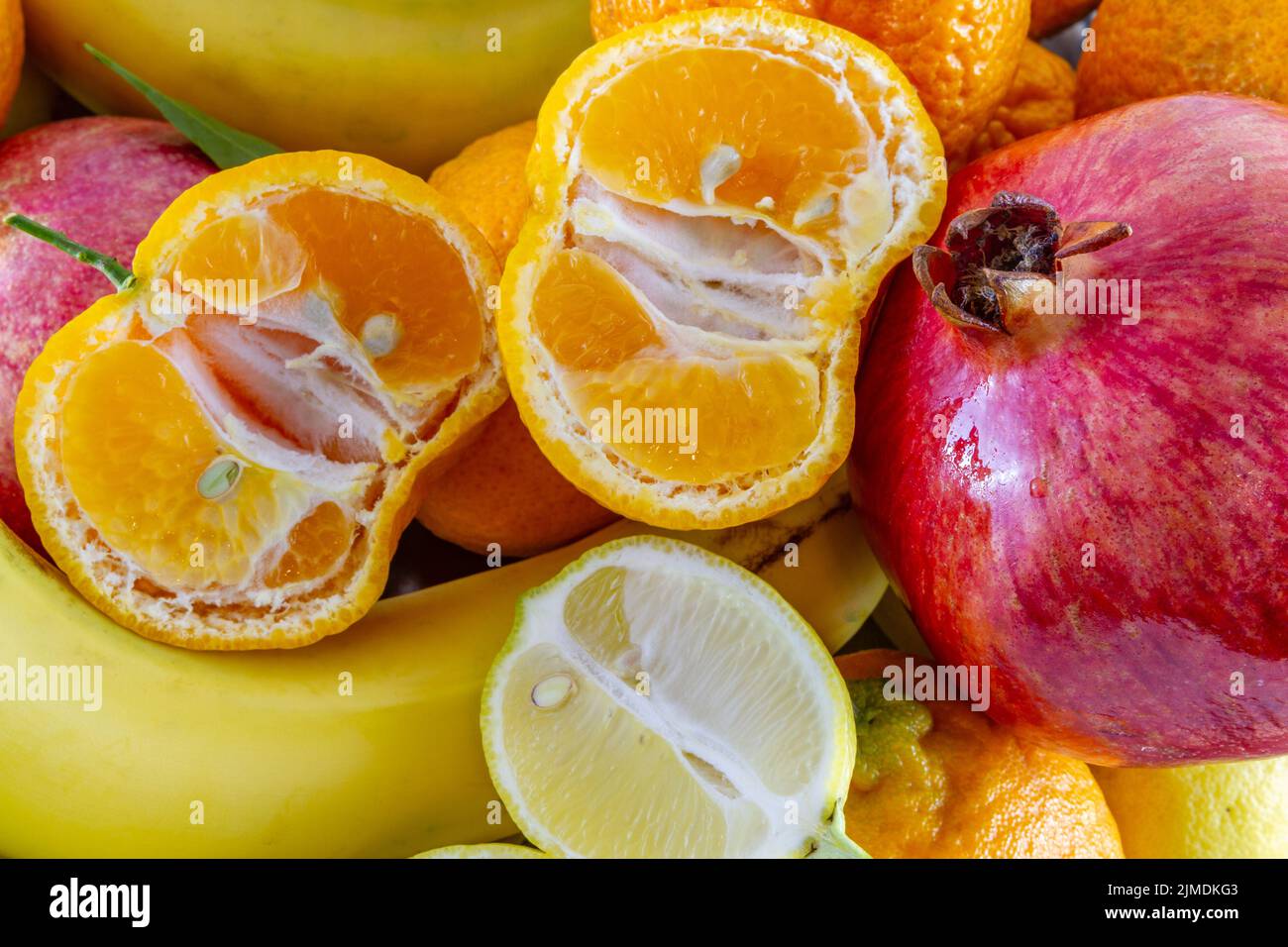 Verschiedene Fruchtarrangements von Bananen, Granatapfel, in Scheiben geschnittene Zitrone und in Scheiben geschnittene Mandarine. Stockfoto