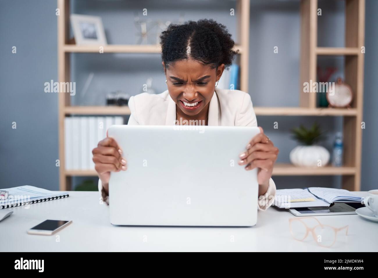 Frustriert, wütend und gestresst junge Geschäftsfrau auf einem Laptop in einem modernen Büro. Frau, die am Arbeitsplatz Ärger über Technologie zeigt. Dame Stockfoto