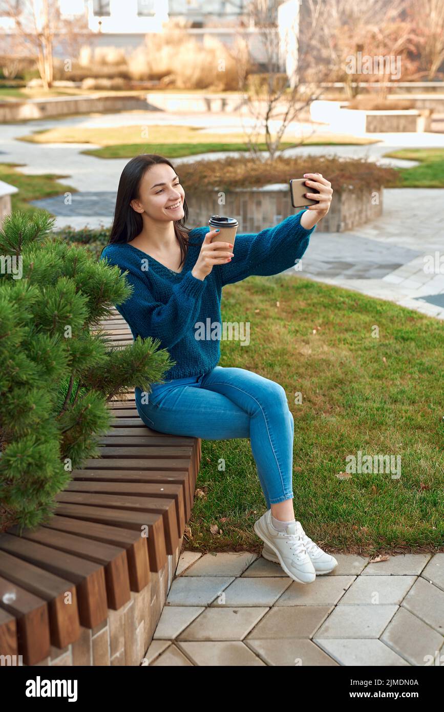 Charmante Dame posiert für Selfie auf einer Bank in schönen Platz Stockfoto