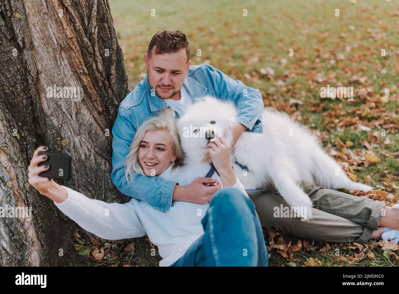 Junger Mann umarmt ihre Freundin und ihren Hund im Freien Stockfoto