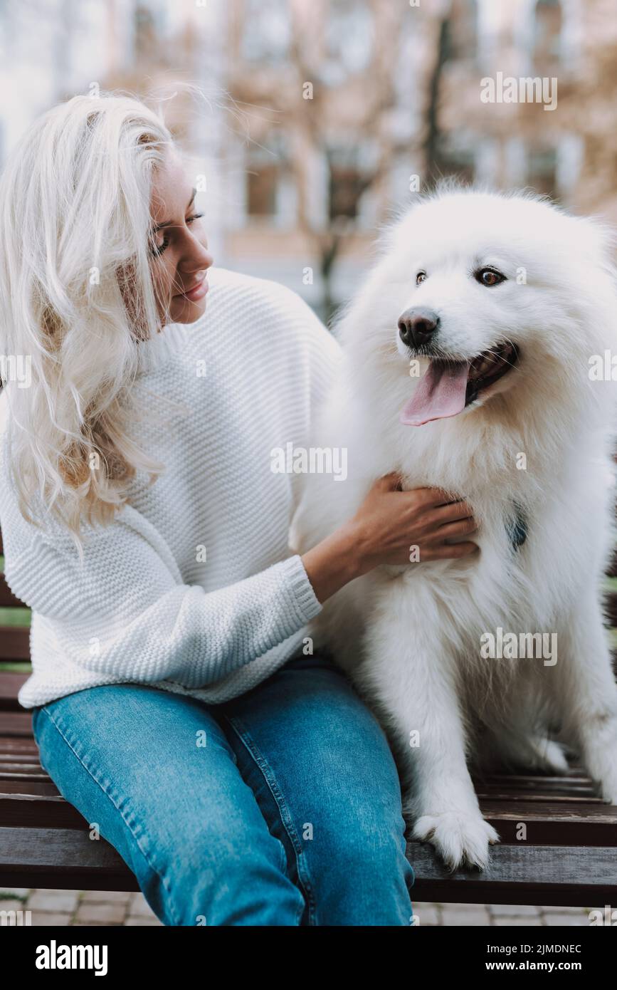 Junge Frau umarmt ihren weißen schönen Hund Stockfoto